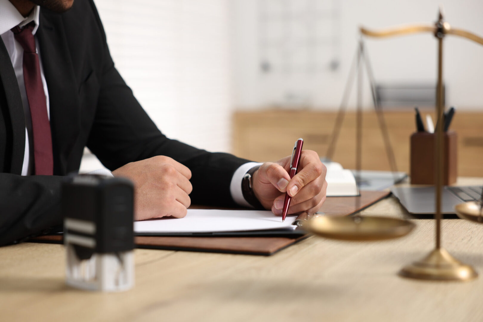 Man writing at desk with scales nearby.